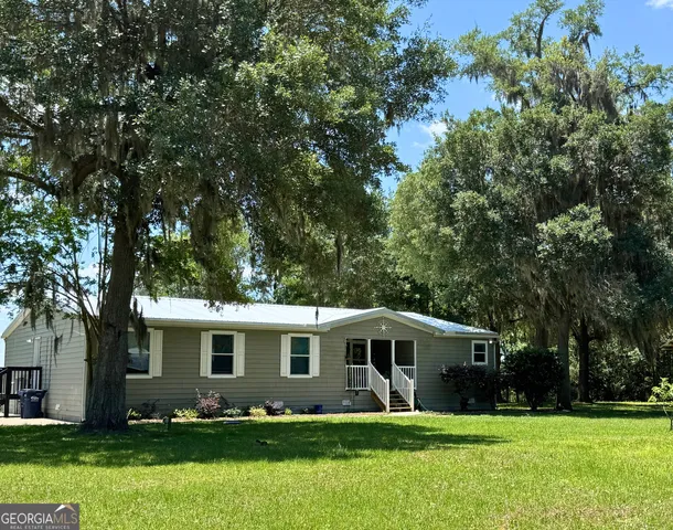 a front view of a house with a garden and trees