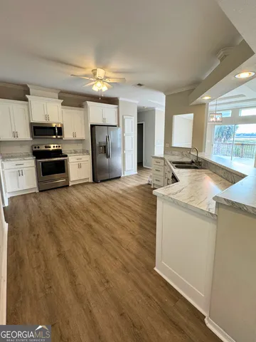 a large kitchen with stainless steel appliances a large counter top a sink and a chandelier