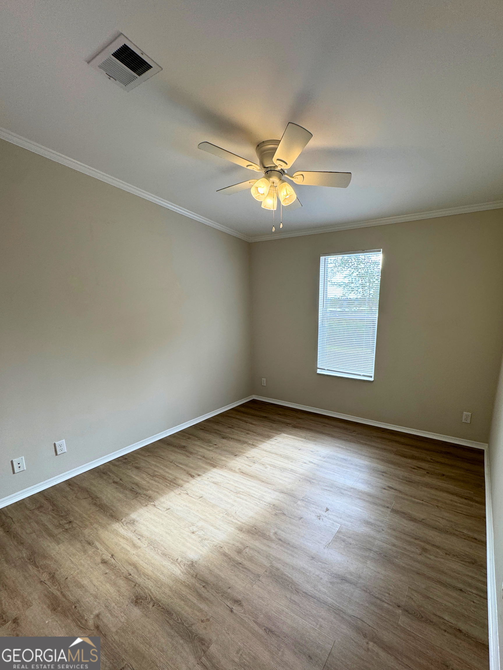 2554 Harrietts Bluff Road Woodbine, GA 31569 - Photo 22 of 35 an empty room with wooden floor chandelier fan and windows