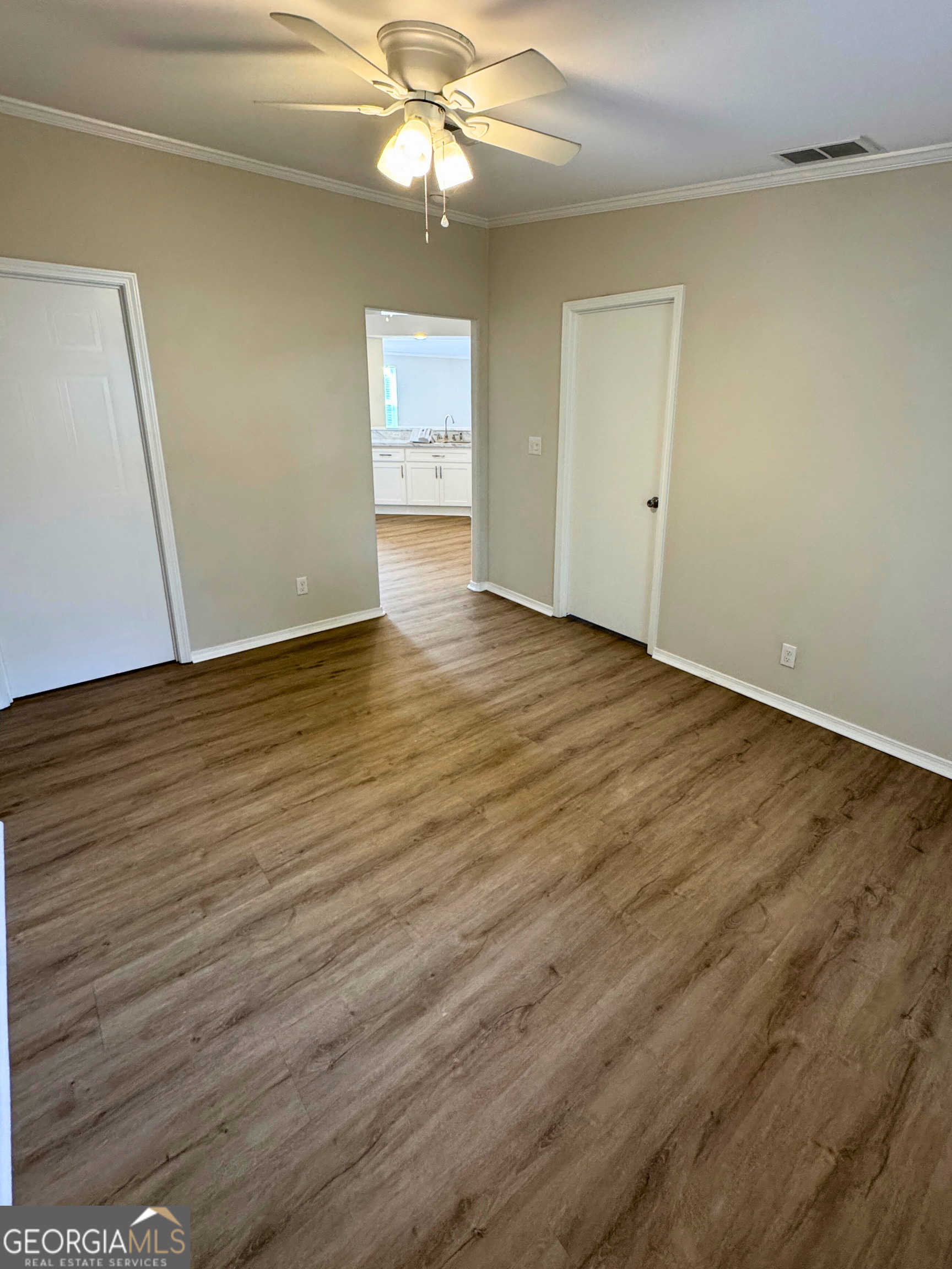 2554 Harrietts Bluff Road Woodbine, GA 31569 - Photo 29 of 35 an empty room with wooden floor chandelier fan and windows