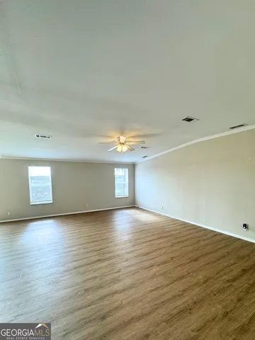 a view of an empty room with window and wooden floor