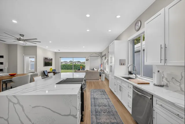 a large kitchen with kitchen island a large window a sink and stainless steel appliances