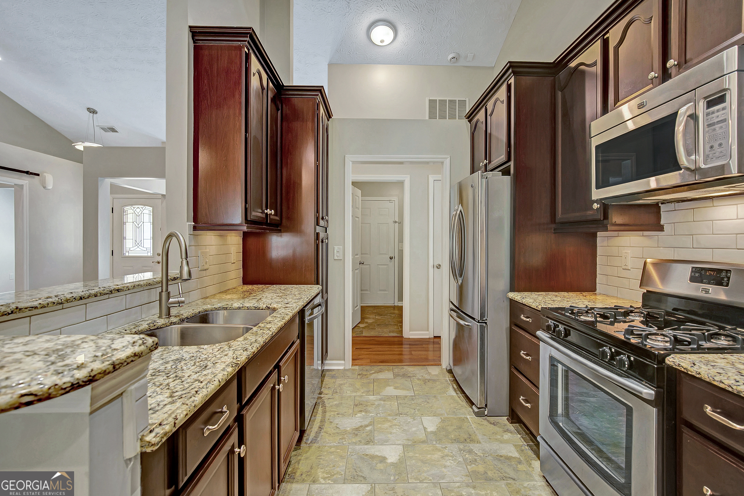 128 Lake Cove Approach Newnan, GA 30265 - Photo 33 of 63 a kitchen with stainless steel appliances granite countertop a sink stove and refrigerator