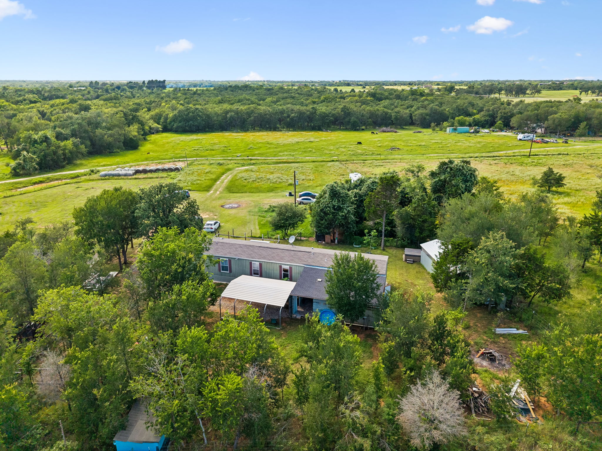 253 North County Line Road, Unit C Elgin, TX 78621 - Photo 36 of 39 An aerial perspective reveals a secluded home amidst verdant fields and a backdrop of dense woodland.