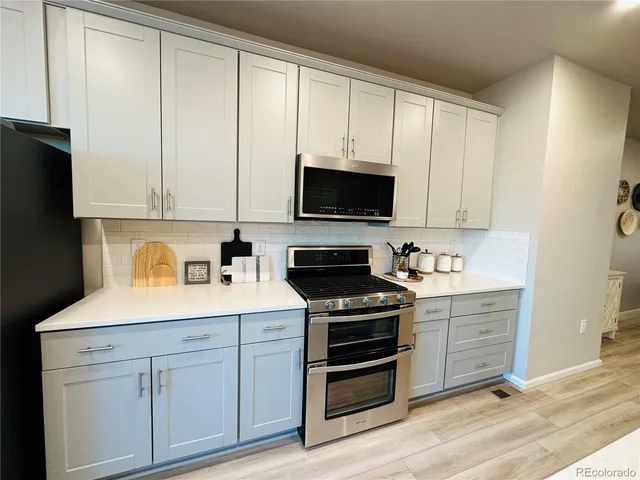 a kitchen with stainless steel appliances white cabinets and a stove top oven