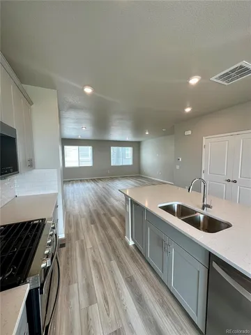 a kitchen with wooden floor a sink and a stove