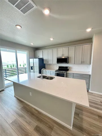 a large kitchen with stainless steel appliances a large counter top a stove and a refrigerator