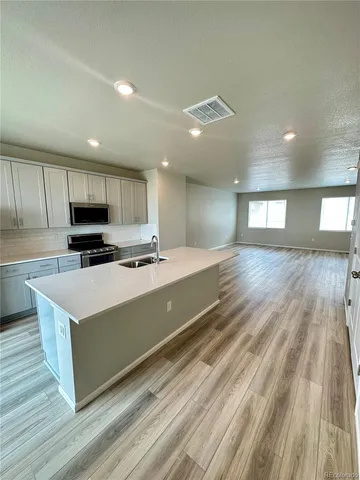 a large kitchen with kitchen island a sink dishwasher a stove and a refrigerator with wooden floor