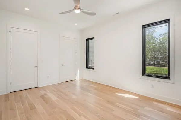 an empty room with wooden floor cabinet and windows