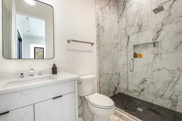 a bathroom with a toilet sink vanity and mirror
