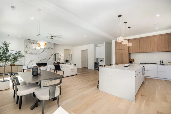 a large white kitchen with a dining table chairs and white cabinets