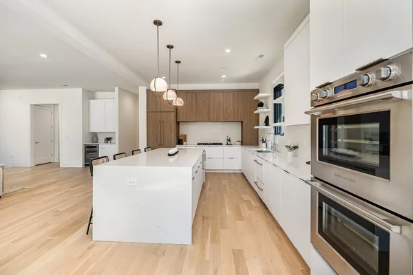 a large kitchen with kitchen island a stove a sink dishwasher and wooden floor