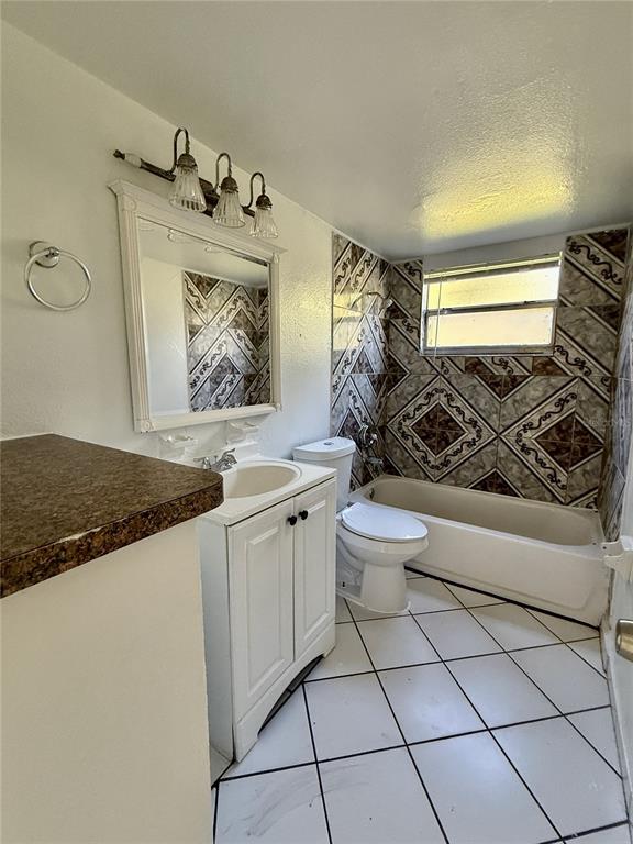 716 Michigan Court, Unit 2 St. Cloud, FL 34769 - Photo 10 of 17 a bathroom with a granite countertop sink a toilet and a shower