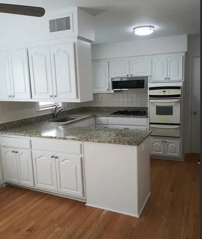 a kitchen with granite countertop a sink stainless steel appliances and cabinets