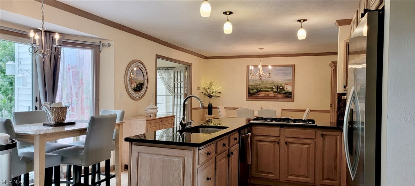7262 Stone Road Independence, OH 44131 - Photo 13 of 34 Kitchen with pendant lighting, a chandelier, dark countertops, ornamental molding, and stainless steel refrigerator