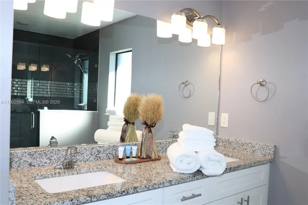 a bathroom with a granite countertop sink and a mirror