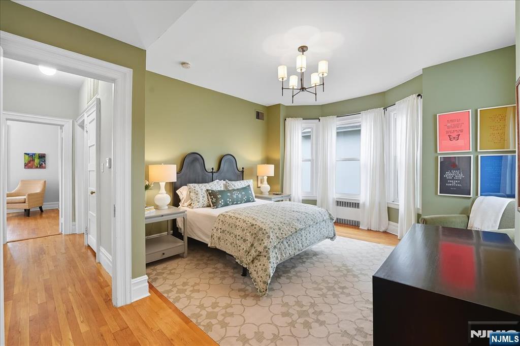 56-58 Bonn Place Weehawken, NJ 07086 - Photo 13 of 29 a spacious bedroom with a bed and a chandelier