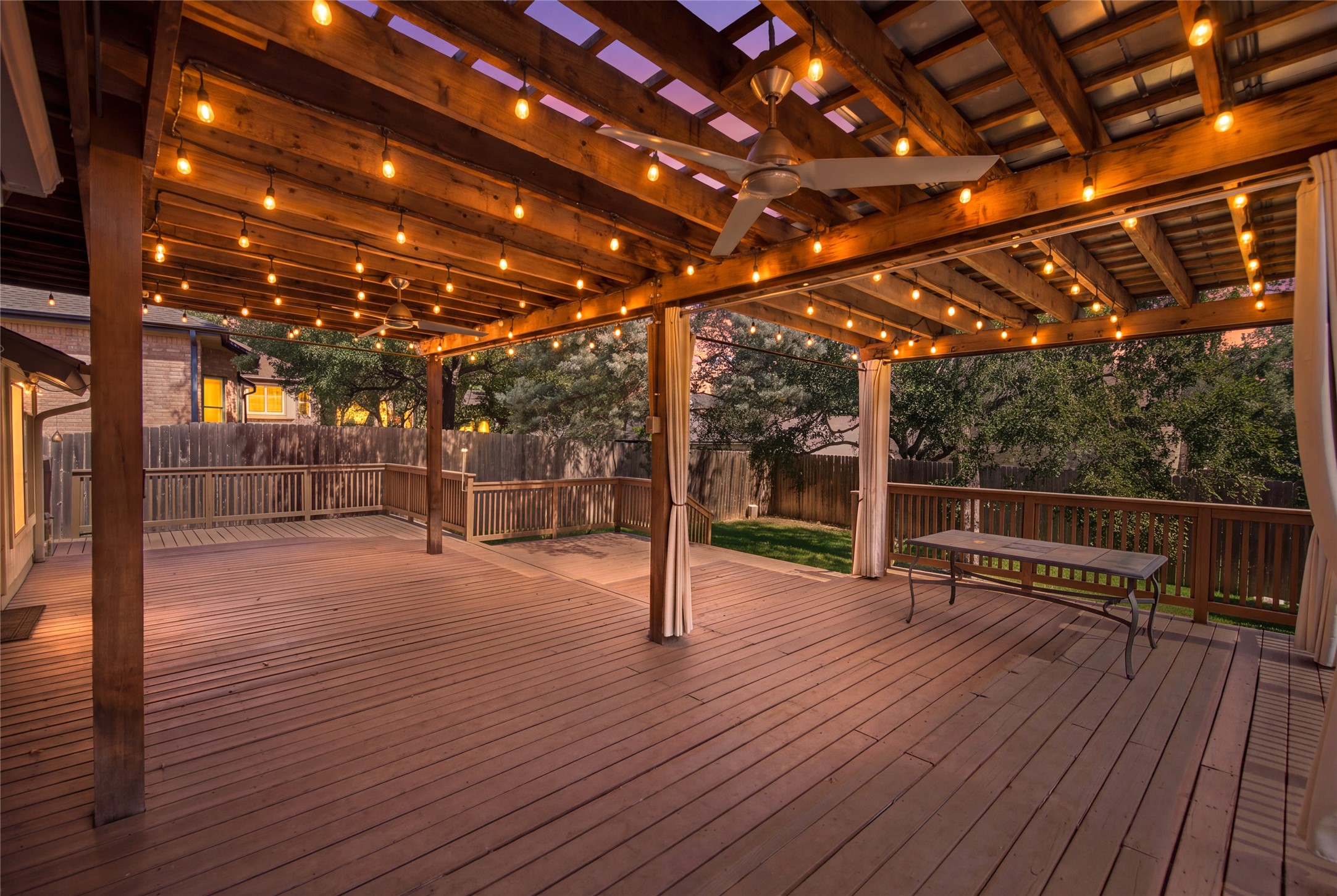 6032 Roxbury Lane Austin, TX 78739 - Photo 3 of 34 A spacious wooden deck extends under a sturdy timber pergola equipped with integrated lighting.