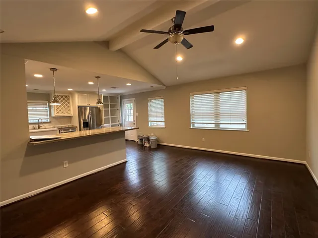 an empty room with wooden floor fan and windows