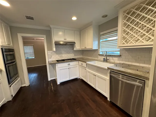 a kitchen with stainless steel appliances a sink a stove a refrigerator and wooden floor