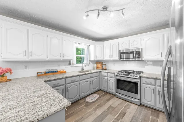 a kitchen with stainless steel appliances granite countertop a stove a sink and a refrigerator