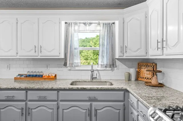a kitchen with granite countertop white cabinets and a window