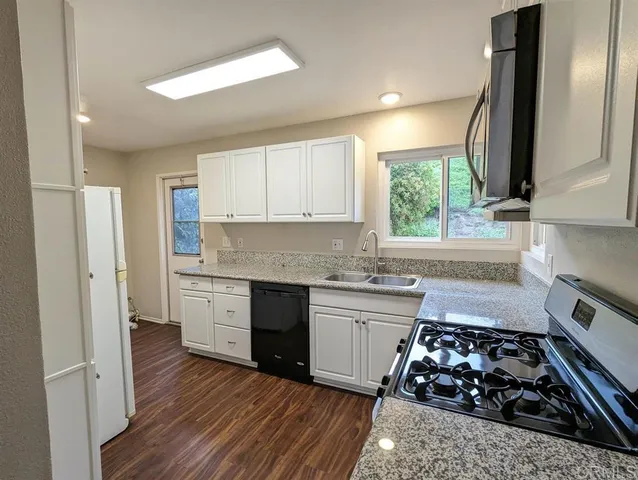 a kitchen with wooden floor a stove a sink and a window