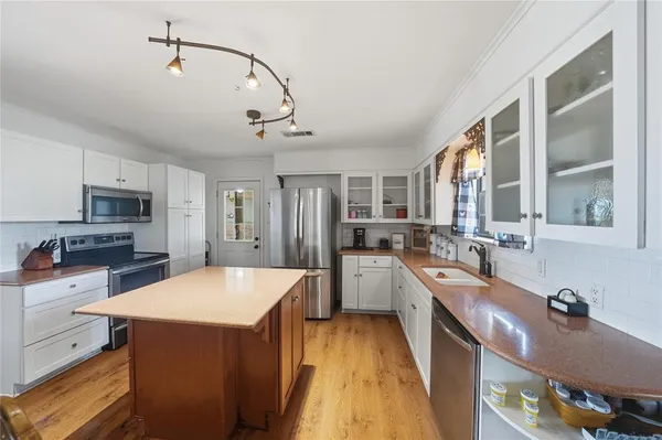a large kitchen with kitchen island a large counter space a sink appliances and cabinets