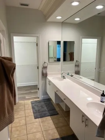 a bathroom with a double vanity sink a large mirror and a shower