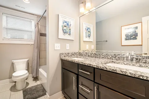 a bathroom with a granite countertop toilet sink and mirror