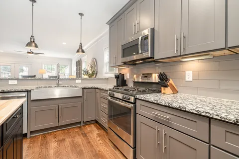 a kitchen with stainless steel appliances granite countertop a sink a stove and a wooden cabinets