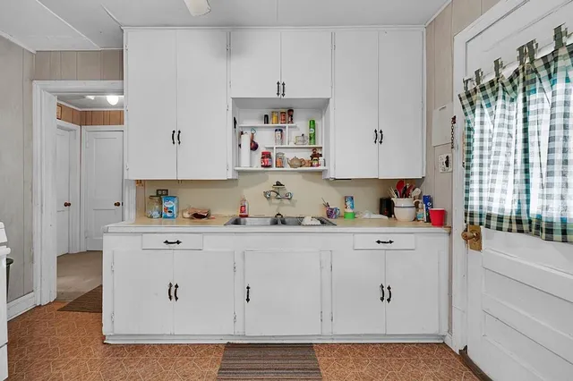 a kitchen with white cabinets and window