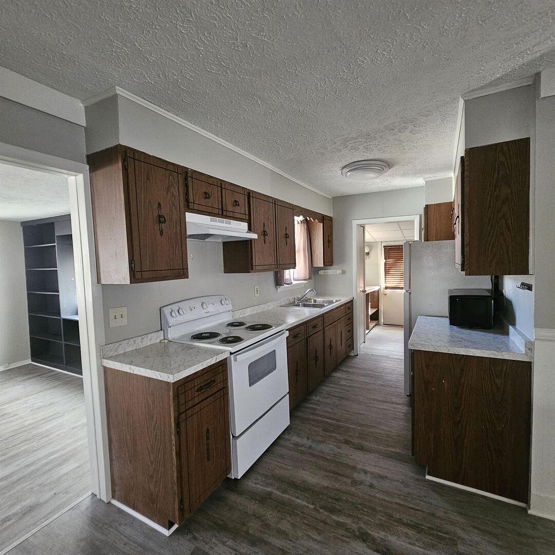 609 Airport Road Mount Vernon, IL 62864 - Photo 18 of 27 a kitchen with stainless steel appliances granite countertop a stove top oven a sink dishwasher and a refrigerator with wooden floor