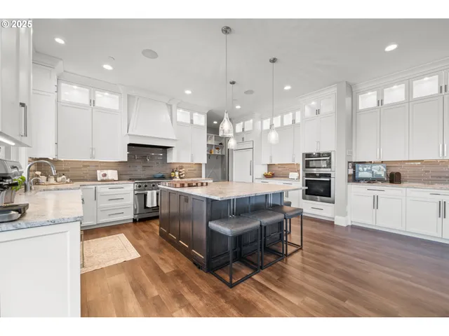 a large kitchen with a large counter top a sink stainless steel appliances and cabinets