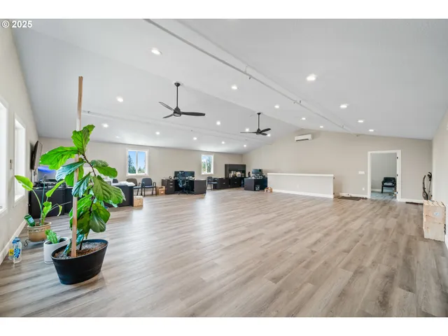 a view of an empty room and kitchen with wooden floor
