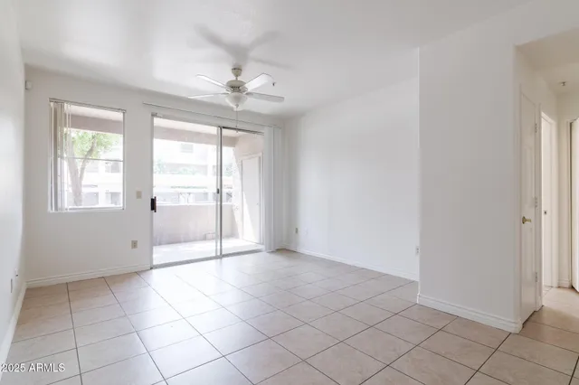 an empty room with windows and chandelier fan
