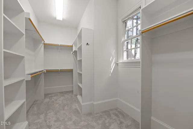 a view of a white house with a yard and table and chairs under an umbrella