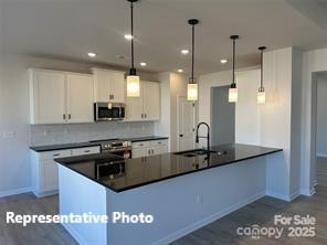 6209 Busch Way Midland, NC 28107 - Photo 10 of 17 a kitchen with stainless steel appliances granite countertop a sink a stove and a refrigerator