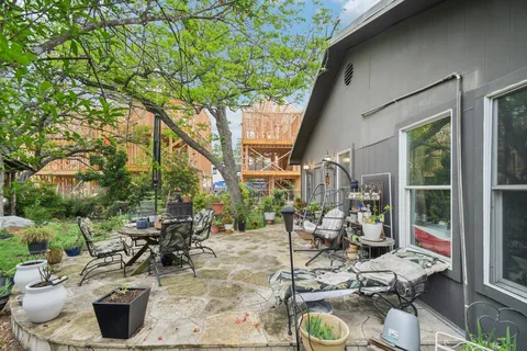 a view of a patio with table and chairs potted plants and large tree