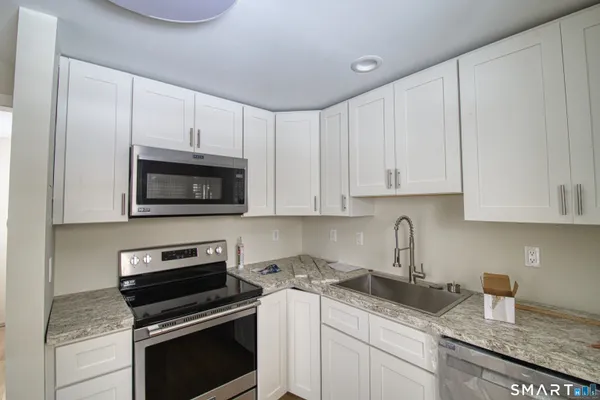 a kitchen with granite countertop white cabinets and stainless steel appliances