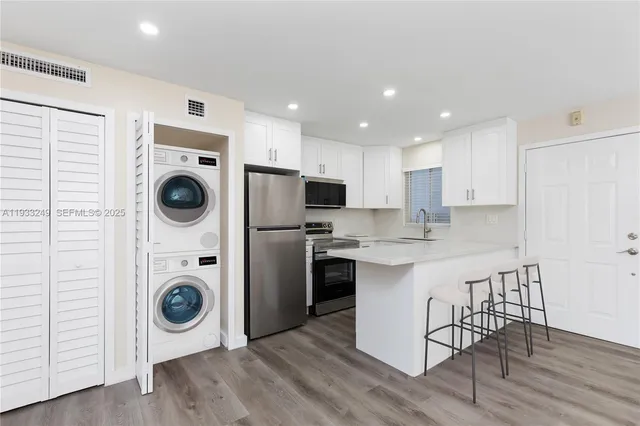 a kitchen with a refrigerator a stove top oven and wooden floor