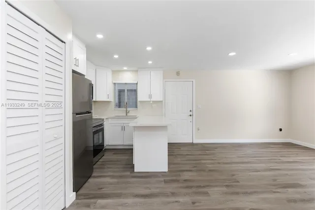 a kitchen with a refrigerator and white cabinets
