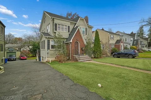 a view of a big house with a big yard and large trees