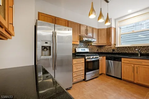 a kitchen with stainless steel appliances granite countertop a refrigerator a stove and a sink