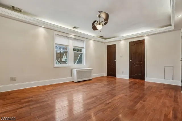 a view of an empty room with a window and wooden floor