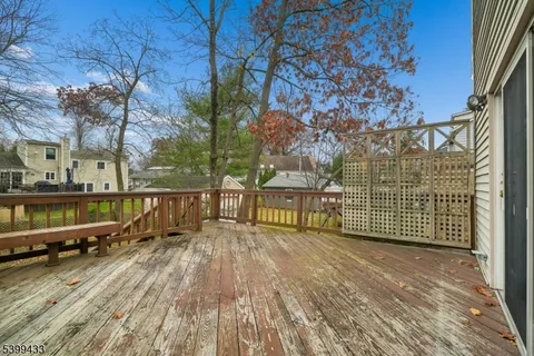 a view of a house with large trees and wooden fence