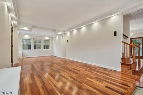 a view of an empty room with window and wooden floor