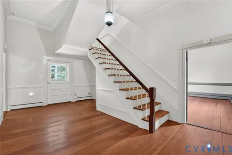 a view of an empty room with wooden floor fireplace and a window