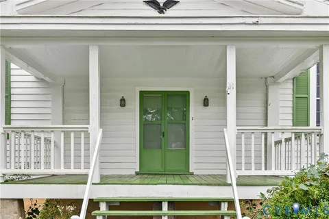an empty room with wooden floor staircase and windows
