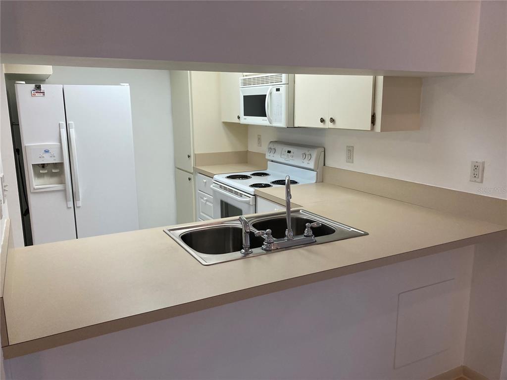 9000 Griggs Road, Unit C Englewood, FL 34224 - Photo 6 of 10 a kitchen with stainless steel appliances a stove a sink and a refrigerator